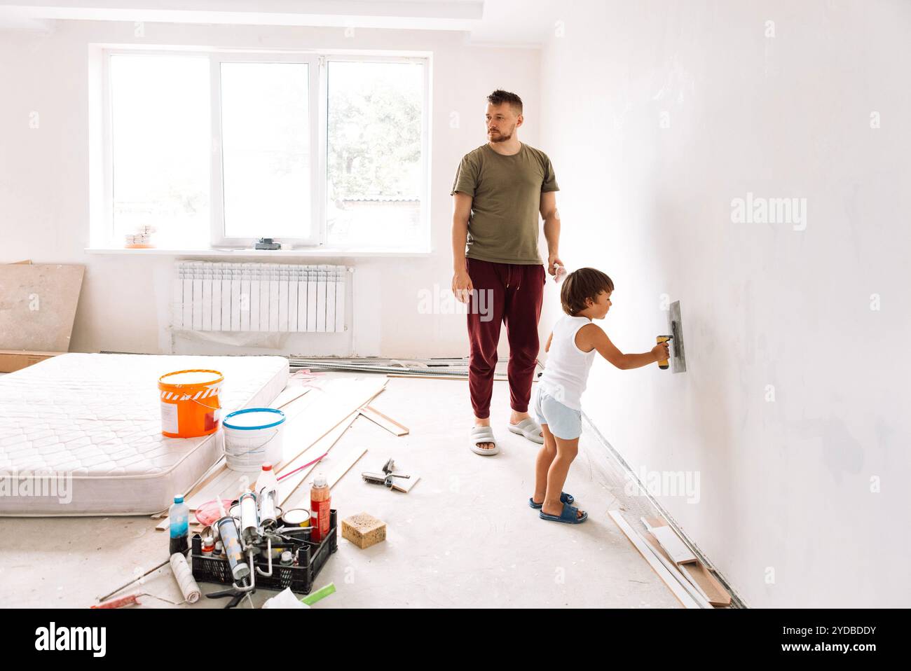 Ristrutturazione dell'appartamento. Il bambino aiuta suo padre a ripulire i muri Foto Stock