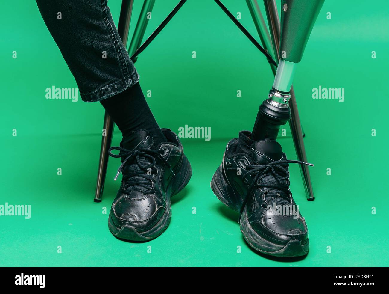 Vista ridotta del giovane disabile con gamba protesica, concetto di arto artificiale. Studio di ripresa su sfondo verde Foto Stock