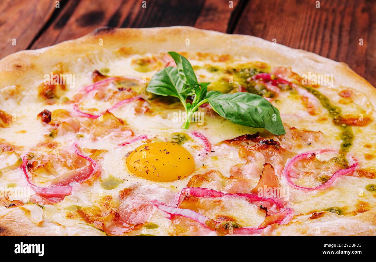 Pizza italiana con tuorlo d'uovo, prosciutto e cipolla Foto Stock