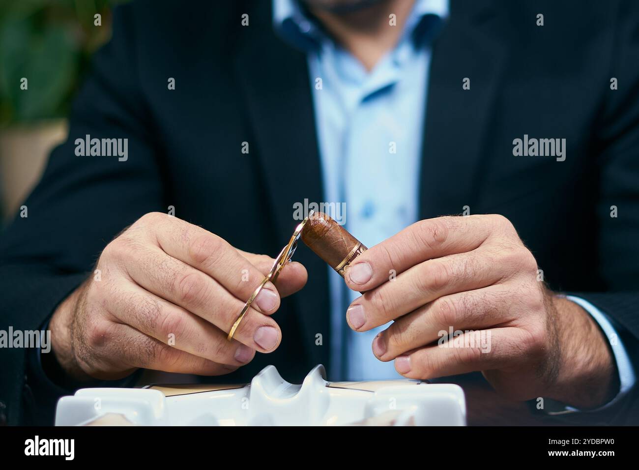 Uomo che taglia il sigaro prima di fumare mentre siede in un ristorante Foto Stock