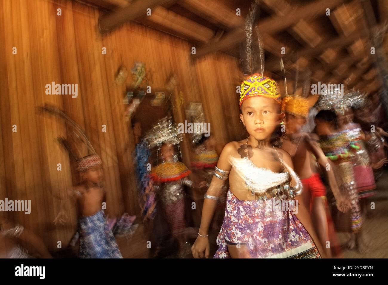 I bambini che si esibiscono in una tradizionale danza di benvenuto all'interno della casa di riposo della comunità IBAN Dayak a Sungai Utik, Kapuas Hulu, Kalimantan Occidentale, Indonesia. Basandosi su una credenza e uno sforzo continui per proteggere il loro ecosistema circostante (foresta, acqua, terra) e le tradizioni culturali, sono state considerate come una delle comunità indigene di maggior successo nel paese nella gestione di attività economiche sostenibili, come il turismo eco-culturale. Foto Stock