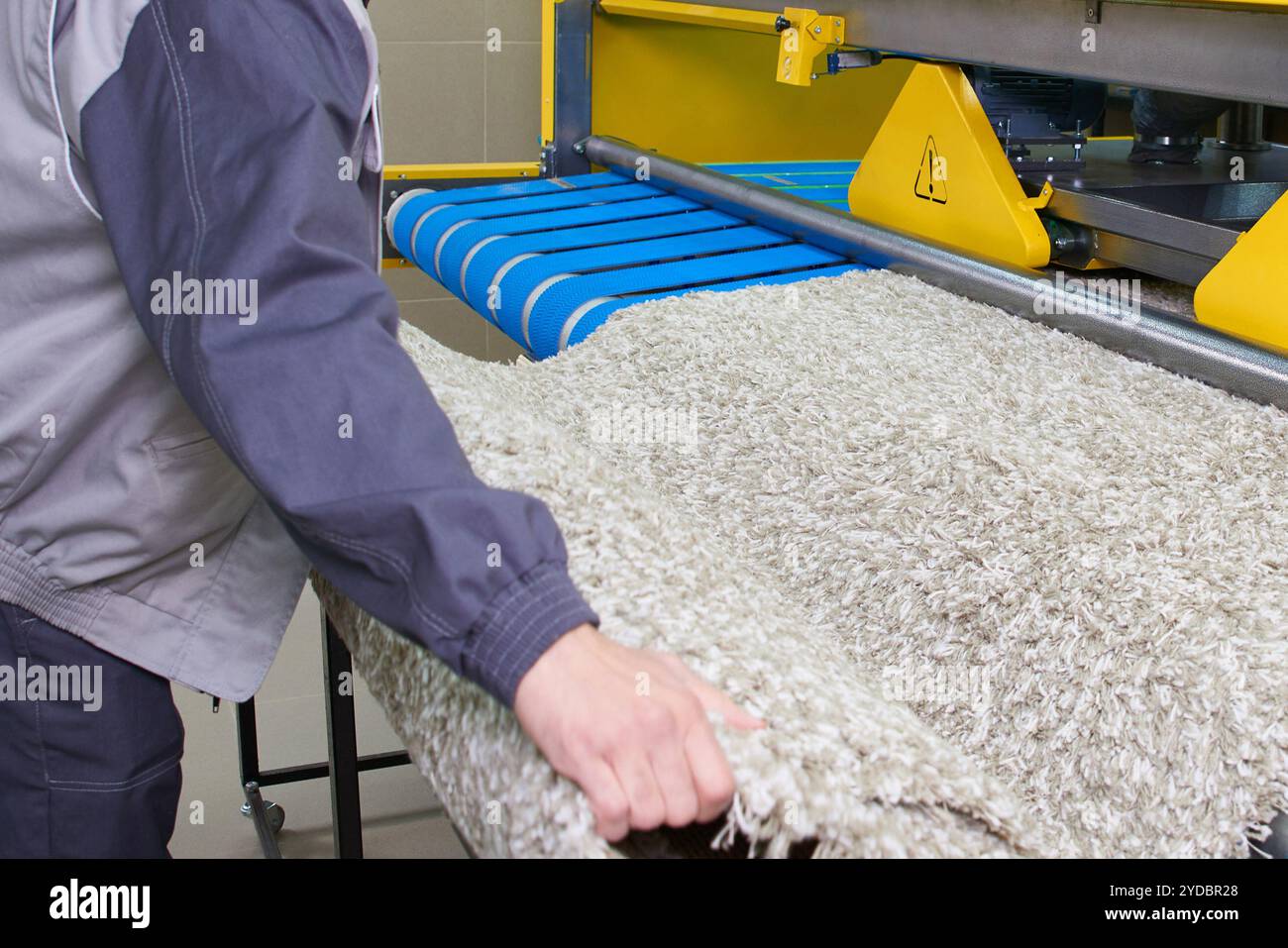 Il lavoratore della lavanderia sta lavorando su una macchina automatica per il lavaggio della moquette in lavaggio a secco Foto Stock