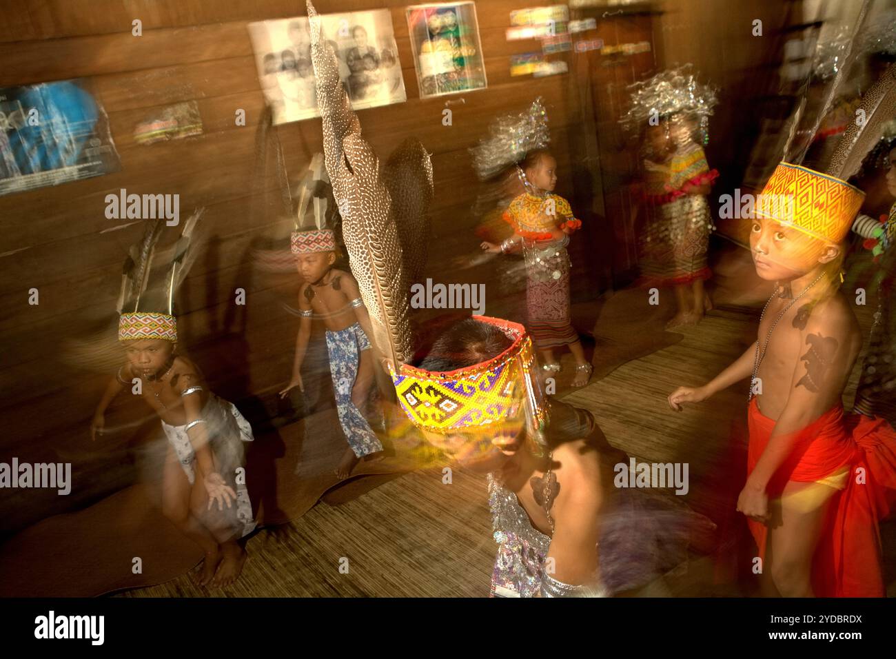 I bambini che si esibiscono in una tradizionale danza di benvenuto all'interno della casa di riposo della comunità IBAN Dayak a Sungai Utik, Kapuas Hulu, Kalimantan Occidentale, Indonesia. Basandosi su una credenza e uno sforzo continui per proteggere il loro ecosistema circostante (foresta, acqua, terra) e le tradizioni culturali, sono state considerate come una delle comunità indigene di maggior successo nel paese nella gestione di attività economiche sostenibili, come il turismo eco-culturale. Foto Stock