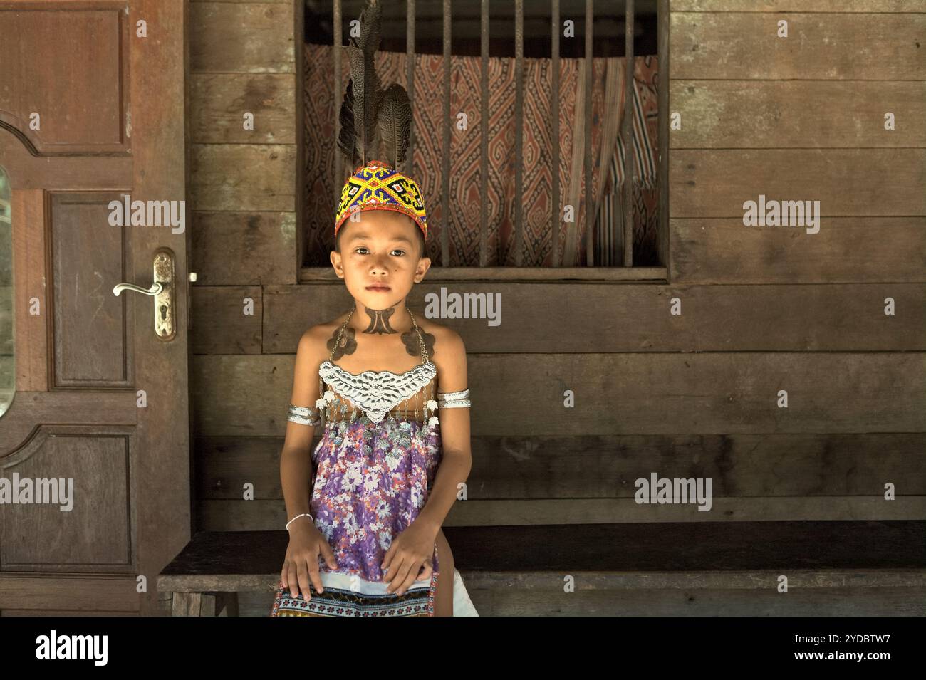 Ritratto di un bambino in abbigliamento tradizionale, con tatuaggi temporanei realizzati con marcatore, dopo aver partecipato a uno spettacolo di danza per accogliere i visitatori presso la casa di riposo della comunità IBAN Dayak a Sungai Utik, Kapuas Hulu, West Kalimantan, Indonesia. Basandosi su una credenza e uno sforzo continui per proteggere il loro ecosistema circostante (foresta, acqua, terra) e le tradizioni culturali, sono state considerate come una delle comunità indigene di maggior successo nel paese nella gestione di attività economiche sostenibili, come il turismo eco-culturale. Foto Stock