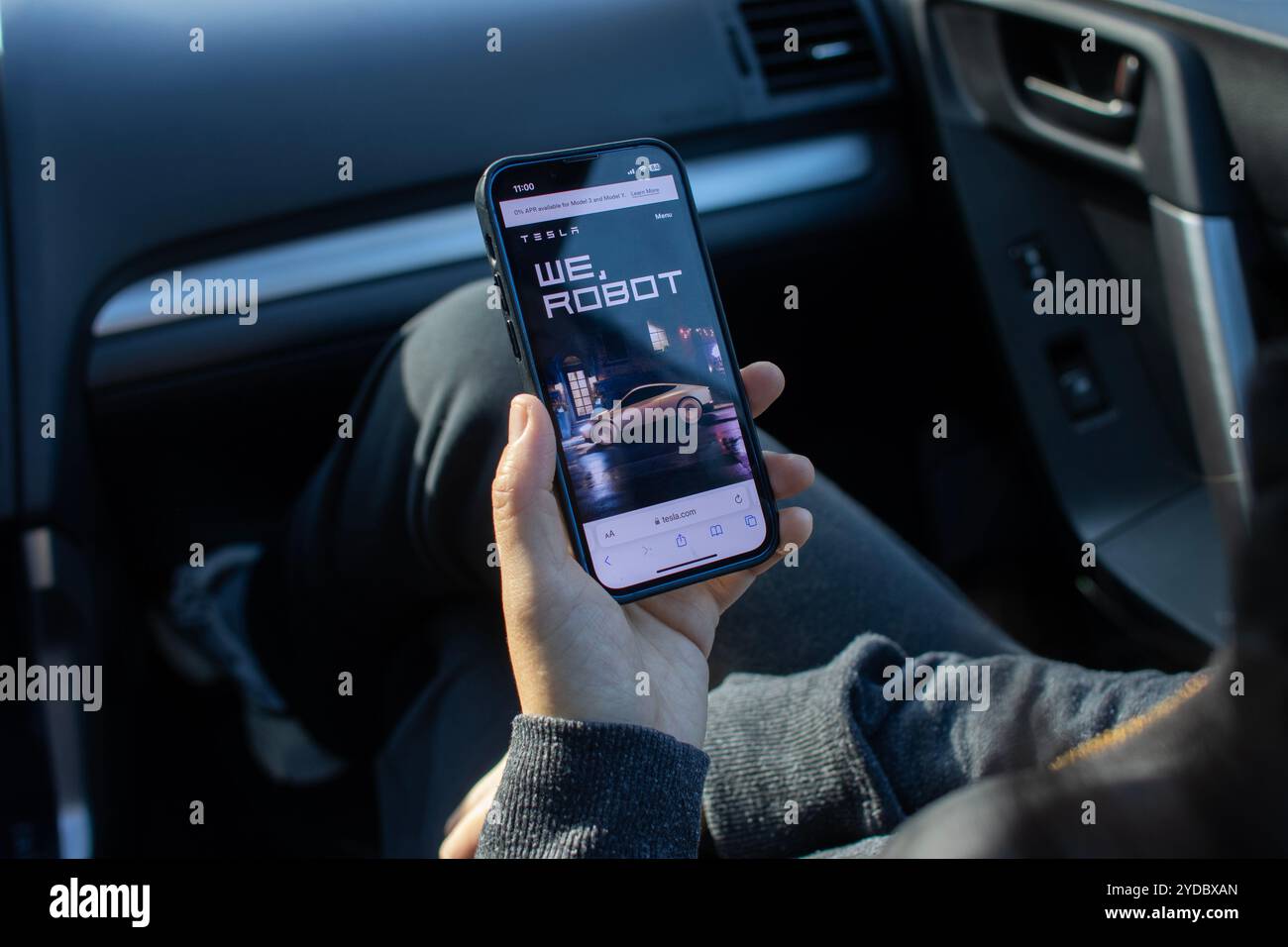 Una donna sfoglia la pagina web dell'evento "noi, robot", Cybercab Unveil di Tesla, sul suo iPhone. Tesla prevede che il suo robotaxi entrerà in produzione entro il 2026. Foto Stock