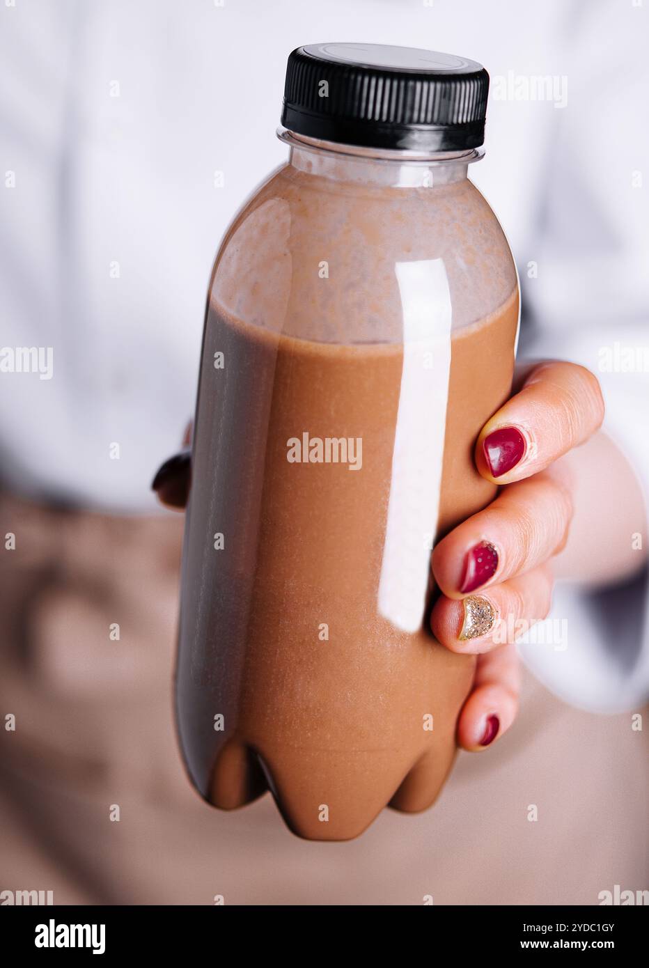 Donna che tiene i frullati di cioccolato in bottiglie di plastica Foto Stock