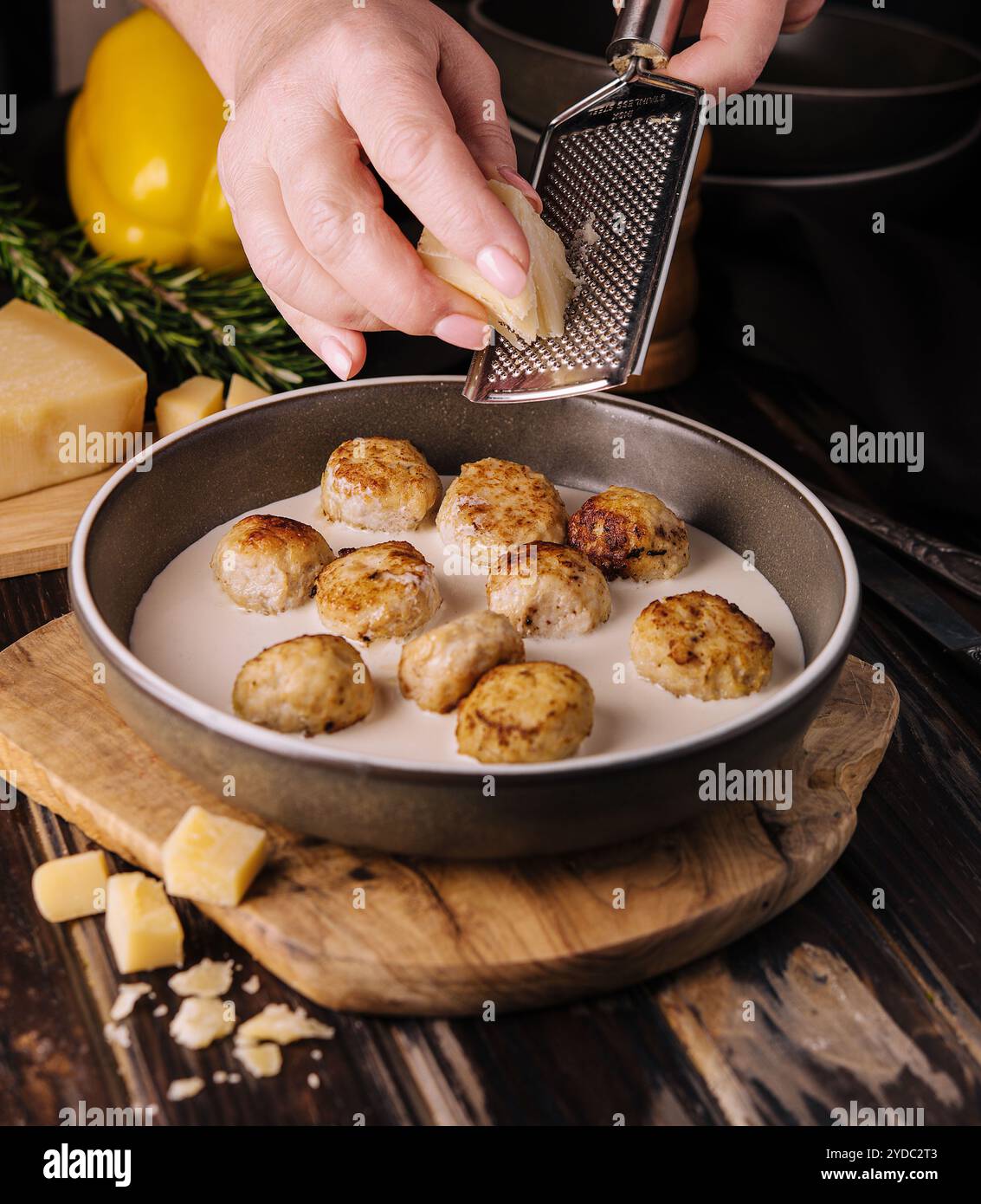 Donna che grattugia il parmigiano sulle polpette in salsa panna Foto Stock