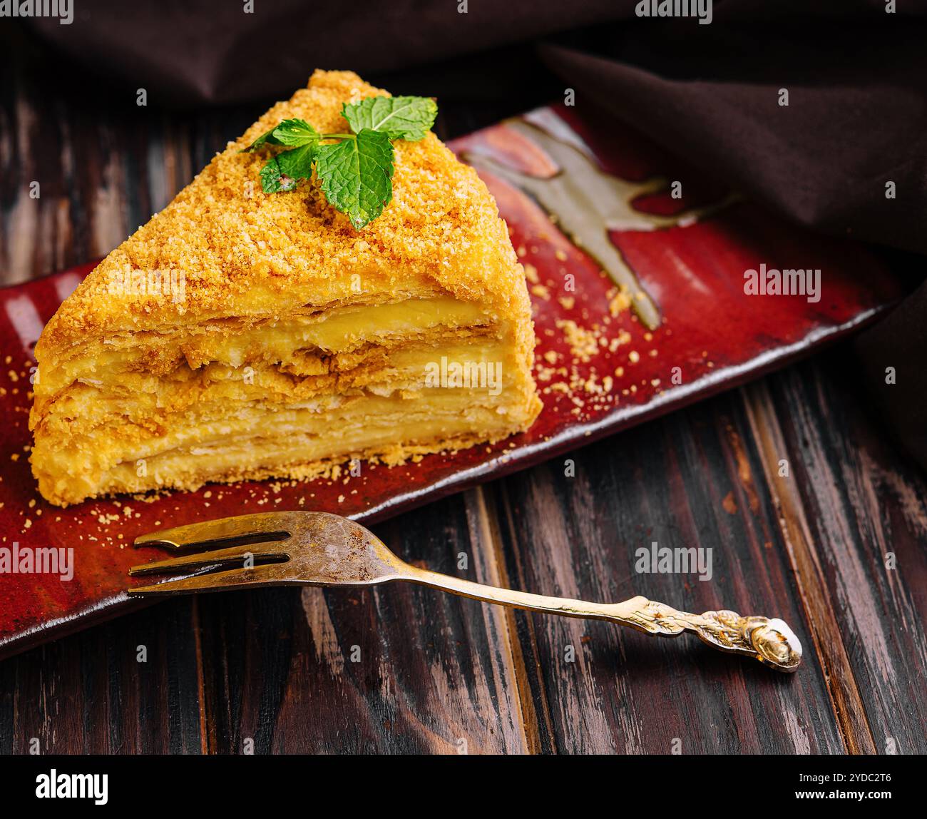 Fetta di torta Napoleone su un piatto di ceramica rossa Foto Stock