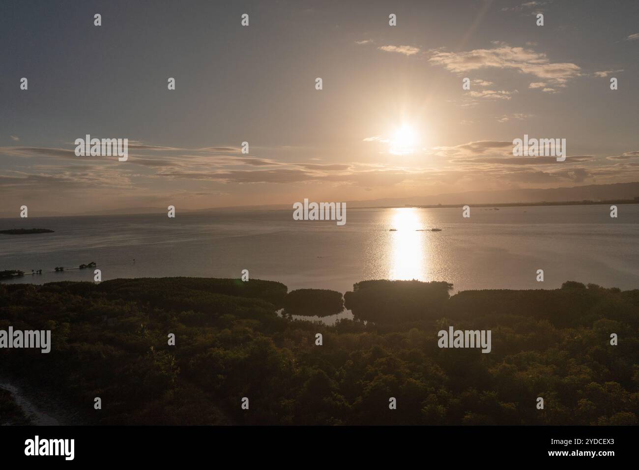 La luce del sole sul mare nell'isola di Olango. Costa tropicale con foresta di mangrovie con riflesso del tramonto. Lapu-Lapu, Filippine. Foto Stock