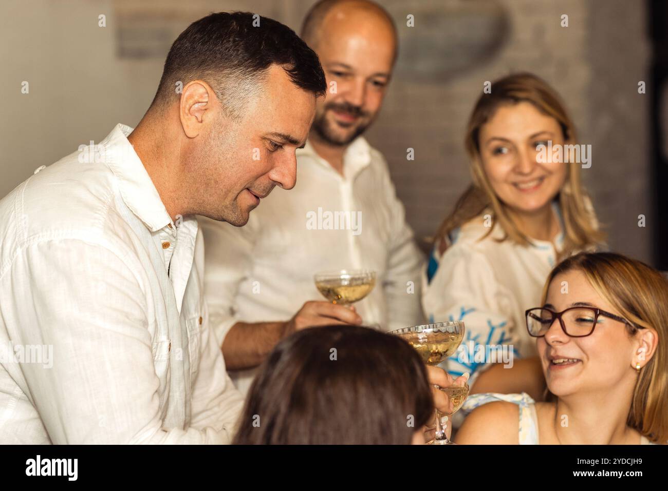 Una riunione di famiglia festiva. I parenti e gli amici fanno un bicchierino e bevono champagne. Gli uomini e le donne brindano alla ragazza di compleanno e si divertono Foto Stock