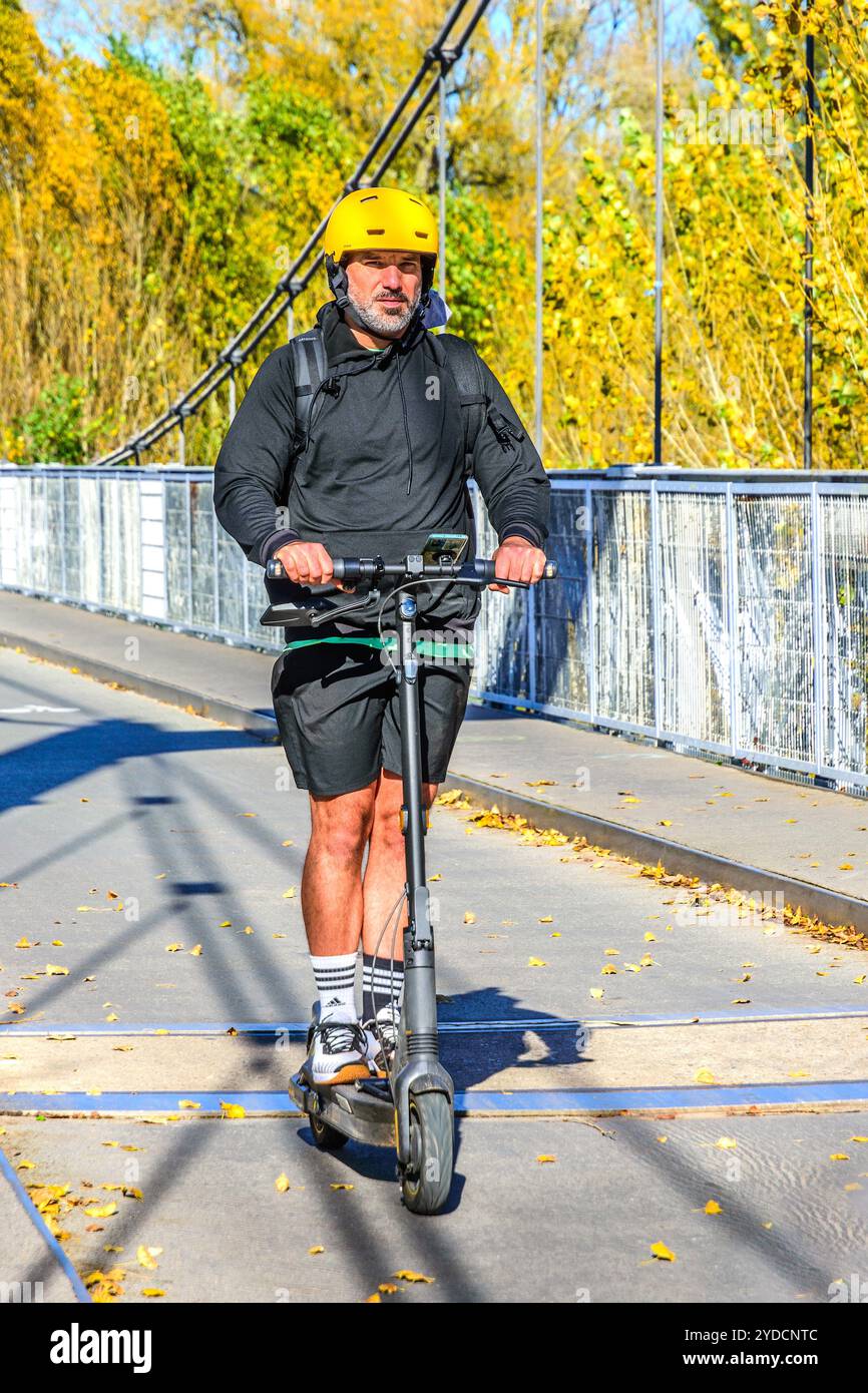 Uomo a bordo di uno scooter elettrico che attraversa il ponte sospeso non adibito al traffico - Tours, Indre-et-Loire (37), Francia. Foto Stock