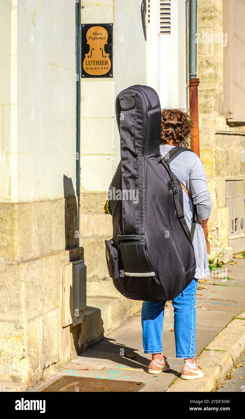 Studente di musica che porta un violoncello in una custodia di stoffa sulla schiena - Tours, Indre-et-Loire (37), Francia. Foto Stock