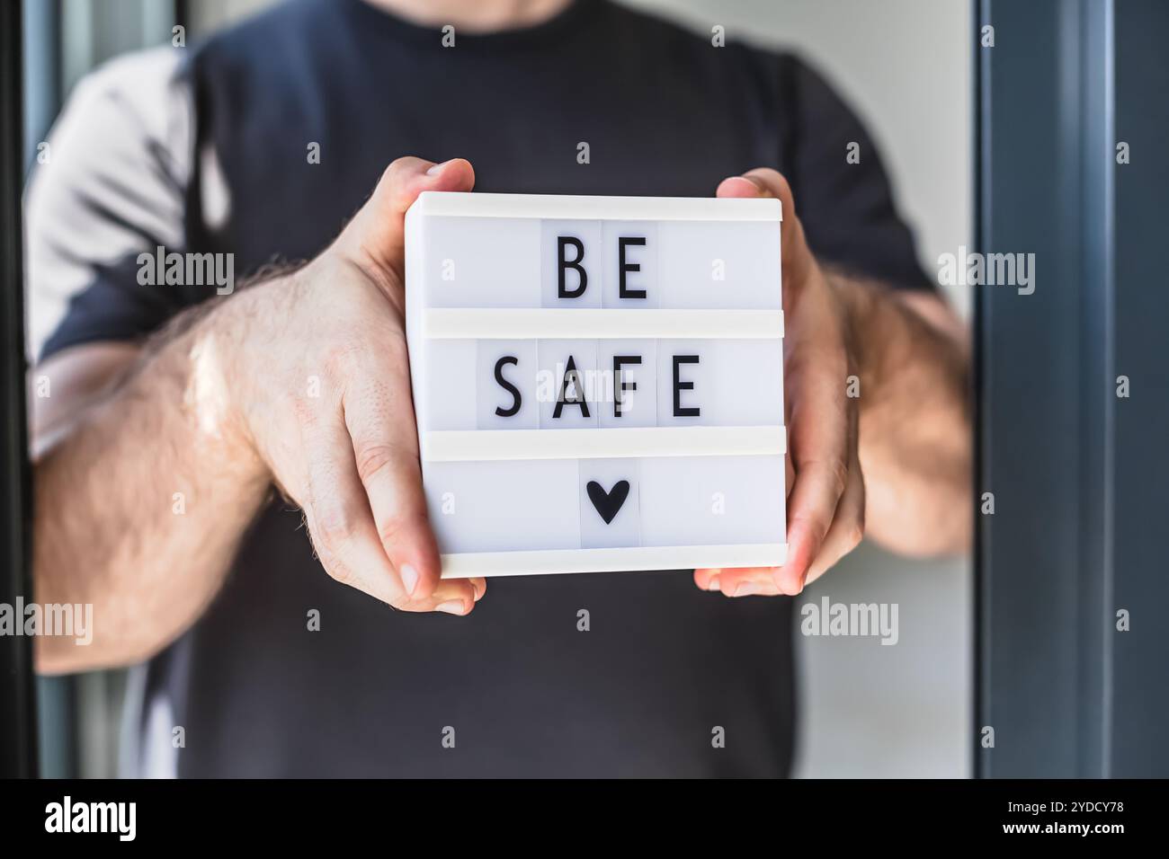 L'uomo che tiene la scatola luminosa con il testo sia al sicuro in mano Foto Stock