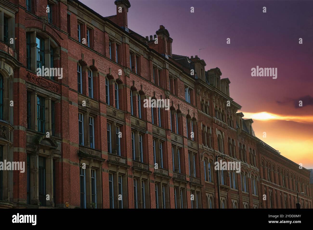Un edificio in mattoni con molte finestre, che si estende verso un cielo al tramonto a Manchester, Regno Unito. Foto Stock