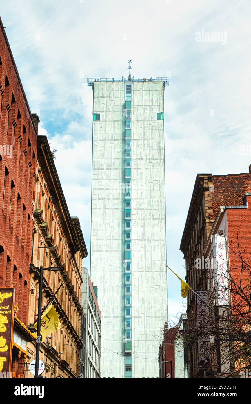 Un alto edificio bianco con un motivo a griglia e una striscia verticale di finestre domina il centro dell'immagine. Due edifici in mattoni su entrambi i lati del telaio t Foto Stock