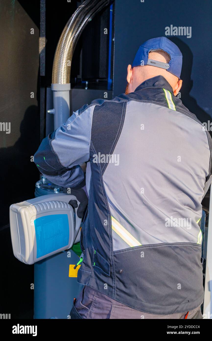 Il tecnico sta riempiendo l'olio nel compressore a vite per ottenere prestazioni ottimali. Foto Stock