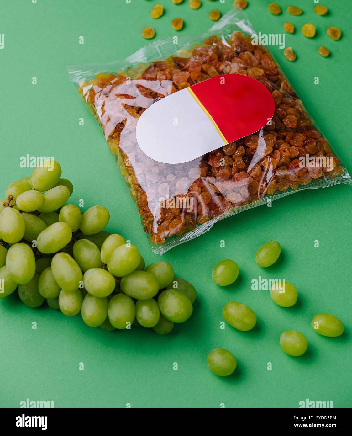Uva passa confezionata e uva su sfondo verde Foto Stock