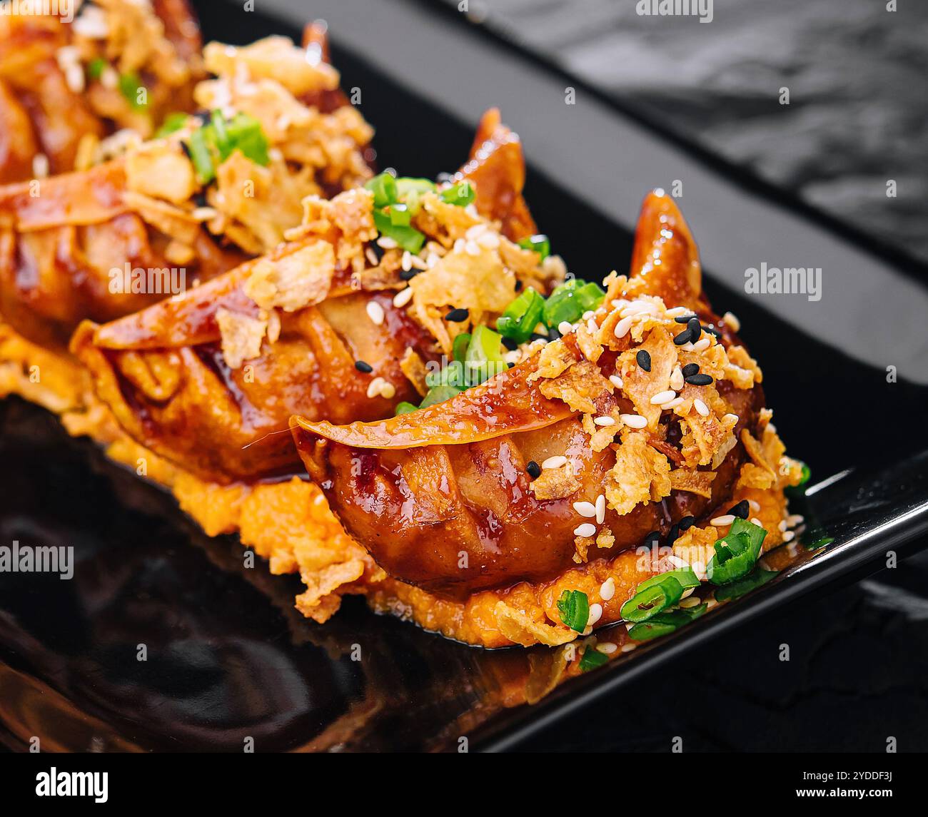 Gnocchi fritti Gyoza su piatto nero Foto Stock