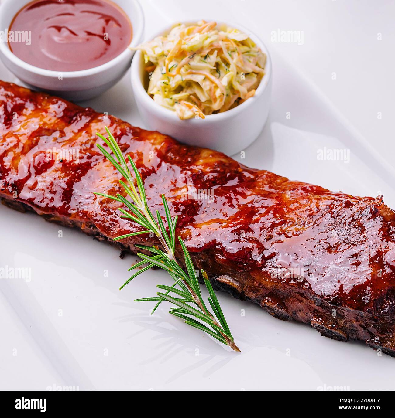 Costolette di maiale grigliate in salsa barbecue e miele con crauti su piatto bianco Foto Stock