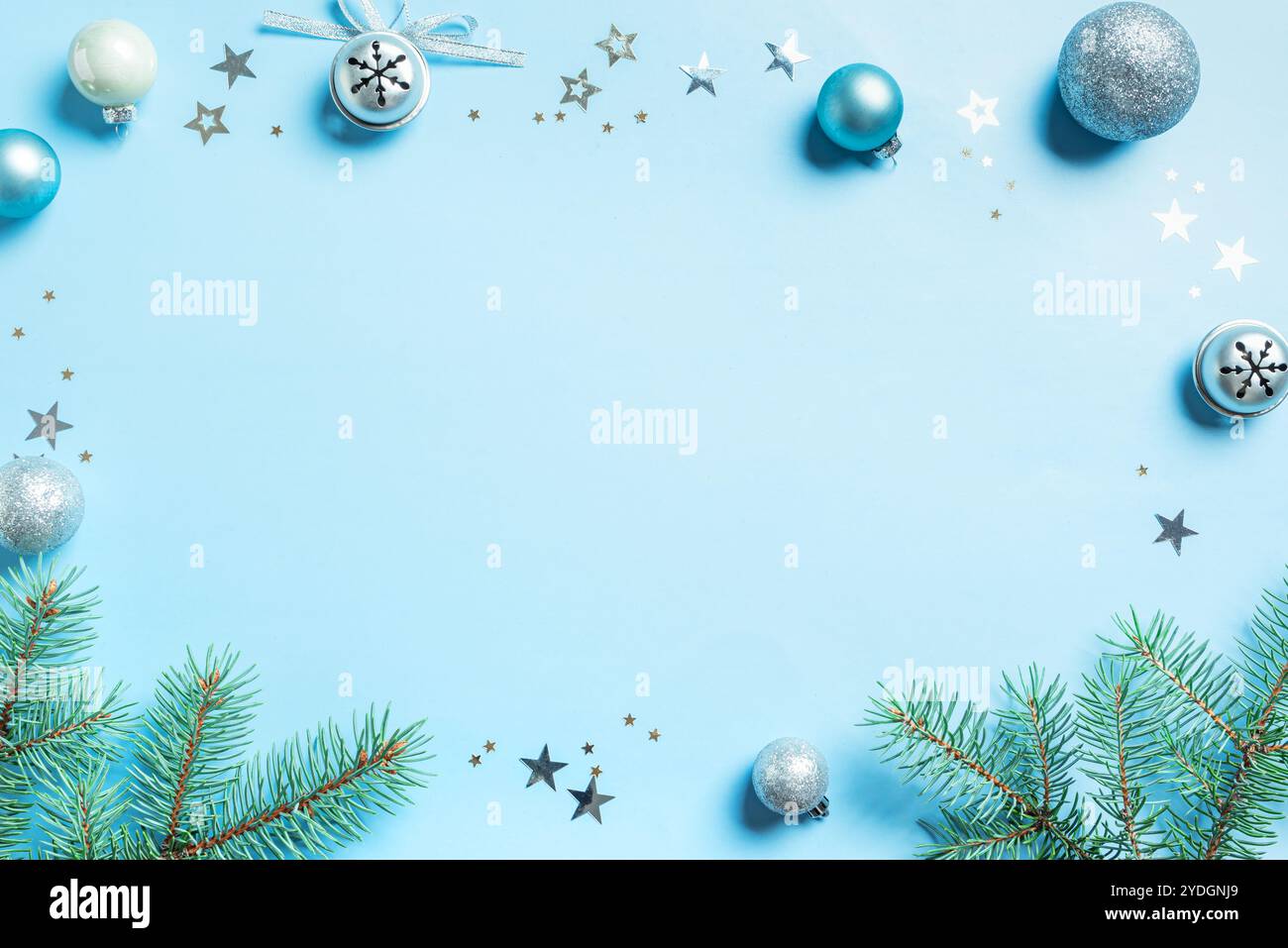 Layout creativo natalizio con rami di abete, ornamenti argentati e stelle su sfondo azzurro, spazio copia. Schema natalizio, festeggiamenti co Foto Stock