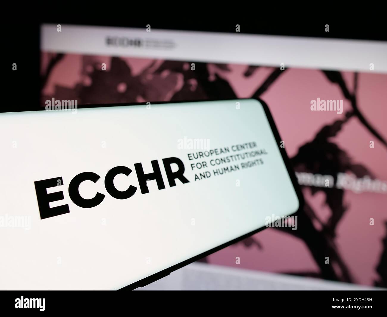 Smartphone con logo dell'organizzazione per i diritti umani ECCHR sullo schermo di fronte al sito web. Mettere a fuoco la parte sinistra del display del telefono. Foto Stock