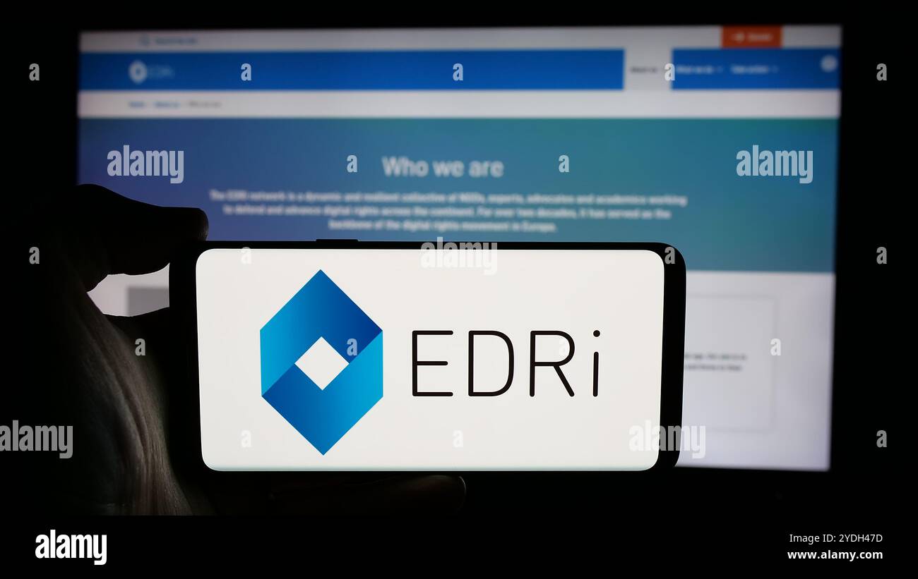 Persona che detiene un cellulare con il logo del gruppo di difesa dei diritti digitali europei (EDRi) sullo schermo di fronte alla pagina web. Mettere a fuoco il display del telefono. Foto Stock