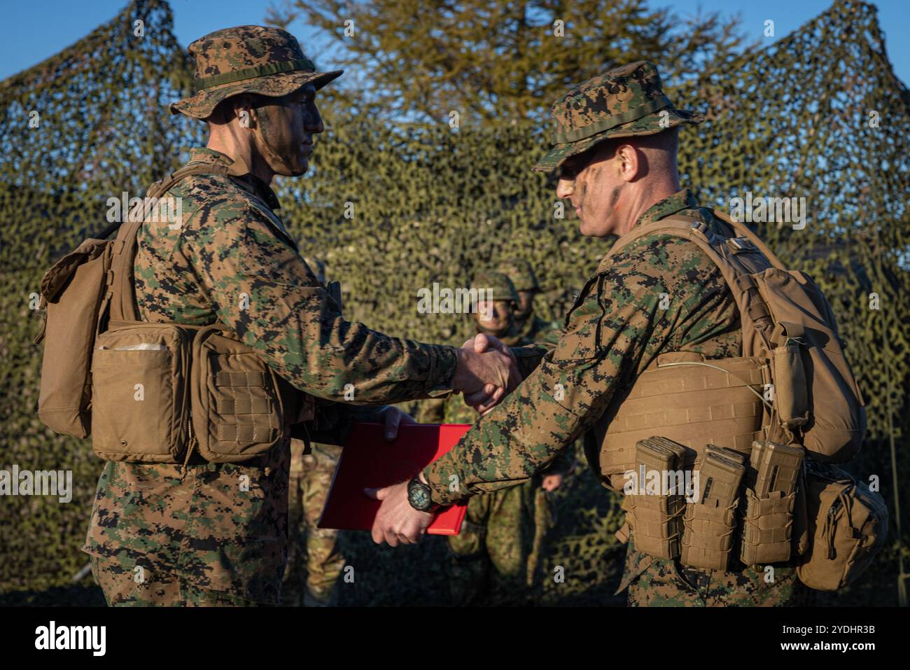 Capitano Andrew Bloem, a destra, ufficiale di artiglieria di campo con 3rd Battalion, 12th Marine Littoral Regiment, 3d Marine Division, Hands staff Sgt. Draw Langsdale, un Field Artillery Operations Marine, il suo certificato di riarmo durante l'esercitazione Keen Sword 25 presso JGSDF Yausubetsu Maneuver area, Hokkaido, Giappone, 24 ottobre 2024. KS25 è un'esercitazione biennale, congiunta e bilaterale sul campo che coinvolge personale militare statunitense e della forza di autodifesa giapponese, progettata per aumentare la prontezza e l'interoperabilità rafforzando al contempo l'alleanza corazzata USA-Giappone. Bloem è nativo di Mich Foto Stock