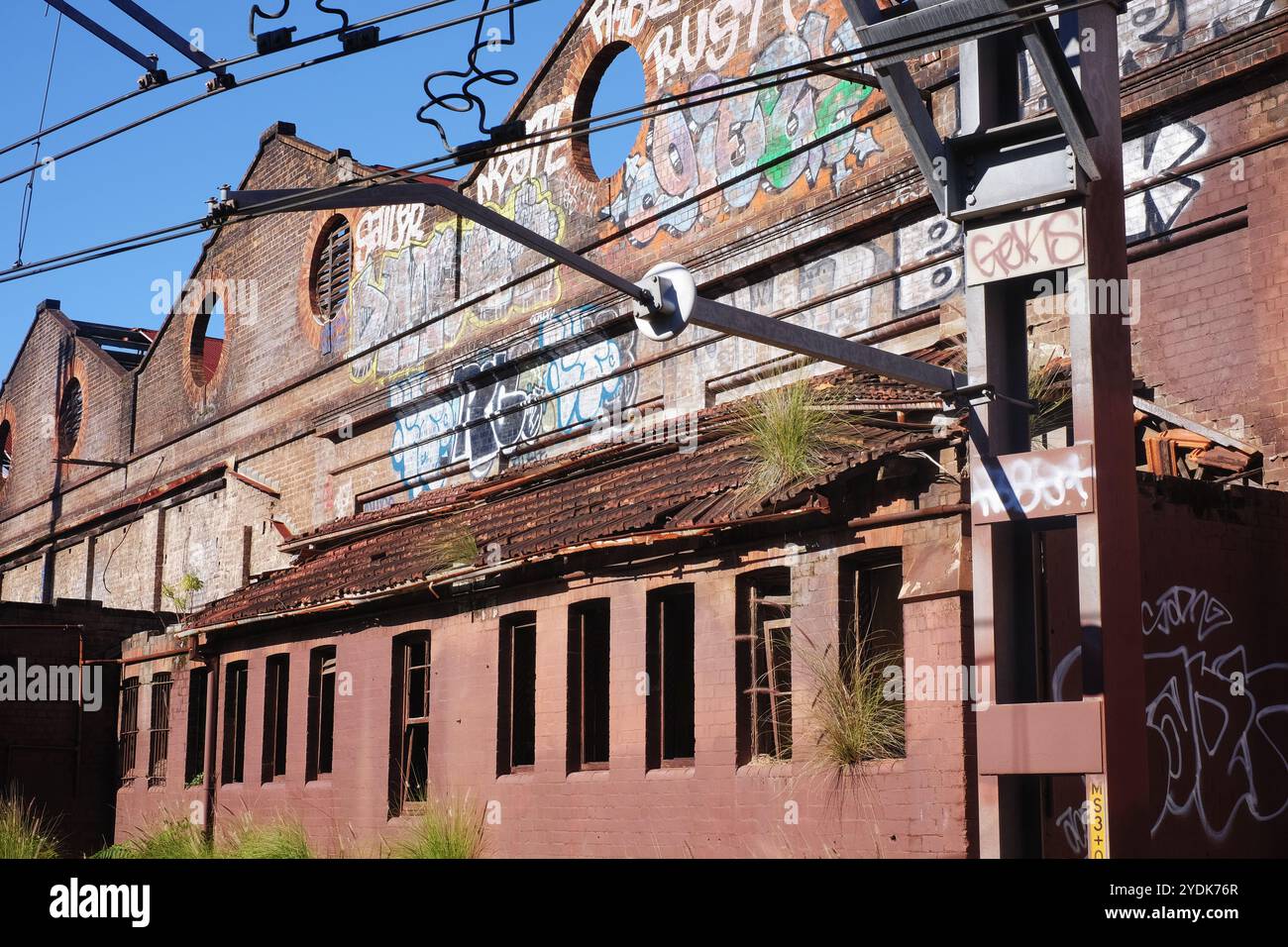 Le vecchie capanne dei tram viste dalla stazione di Newtown, gli edifici industriali in disuso le pareti in mattoni, il tetto delle seghe e i graffiti Foto Stock
