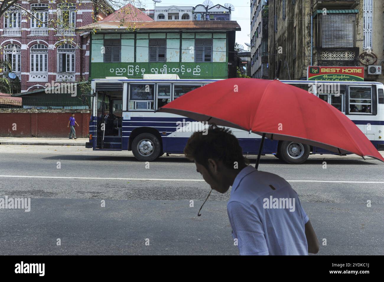 09.11.2015, Yangon, Myanmar, Asia, Un uomo con un ombrello sputa per strada mentre masticava il betel nut, Asia Foto Stock
