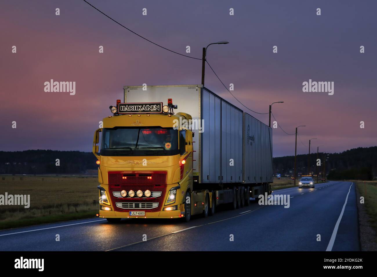 La Volvo FH16 gialla TransHartikainen Ky, splendidamente personalizzata, tira un rimorchio all'inizio dell'inverno all'imbrunire sull'autostrada 52. Salo, Finlandia. 26 novembre 2020 Foto Stock