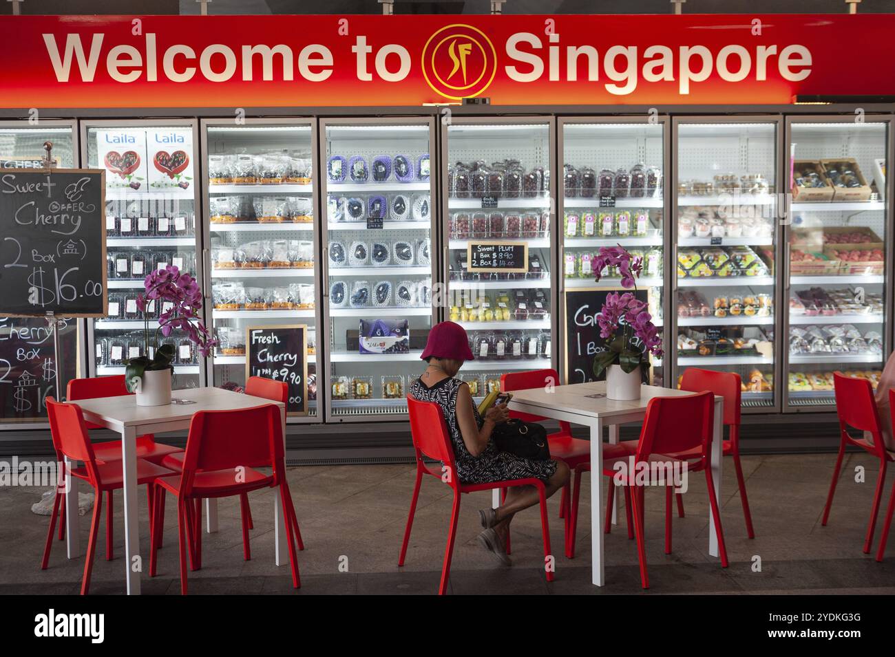 25.07.2019, Singapore, Repubblica di Singapore, Asia, Una donna siede davanti a uno scaffale refrigerato con frutta confezionata a Marina Bay, Asia Foto Stock