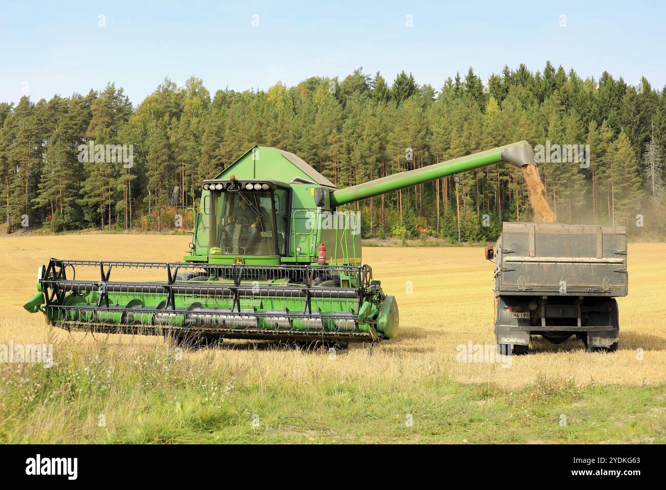 Salo, Finlandia, 8 settembre 2018: La mietitrebbia John Deere scarica la granella raccolta su un rimorchio in una giornata limpida di autunno nel sud della Finlandia, in Europa Foto Stock