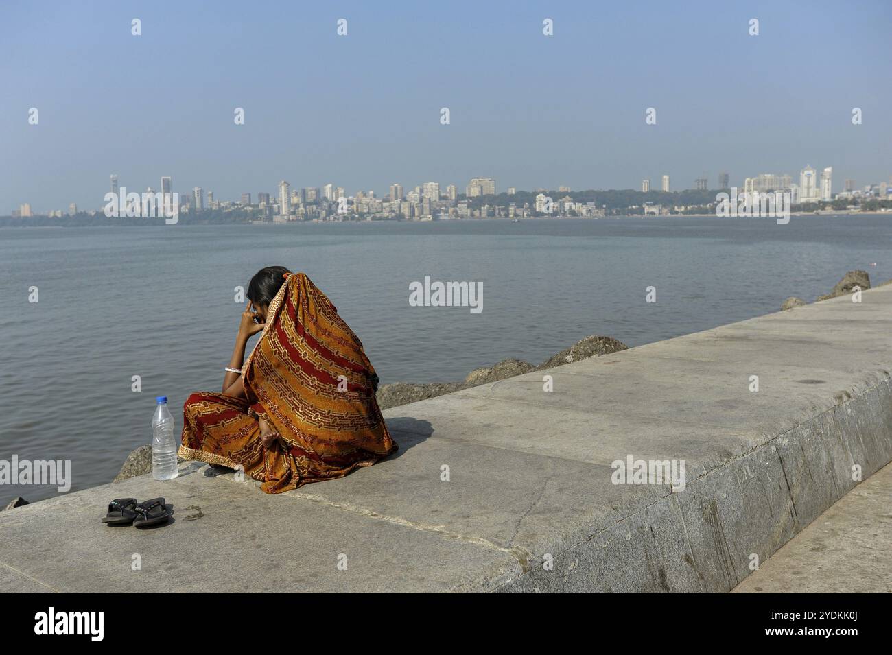 08.12.2011, Mumbai, Maharashtra, India, Asia, una donna siede sul lungomare lungo Marine Drive con lo skyline di Malabar Hill sul retro Foto Stock