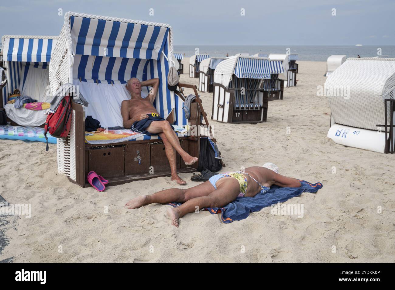 27.07.2024, Ahlbeck, Usedom, Meclemburgo-Pomerania occidentale, Germania, Europa, i turisti prendono il sole sulle tradizionali sedie a sdraio e sulla sabbia Foto Stock