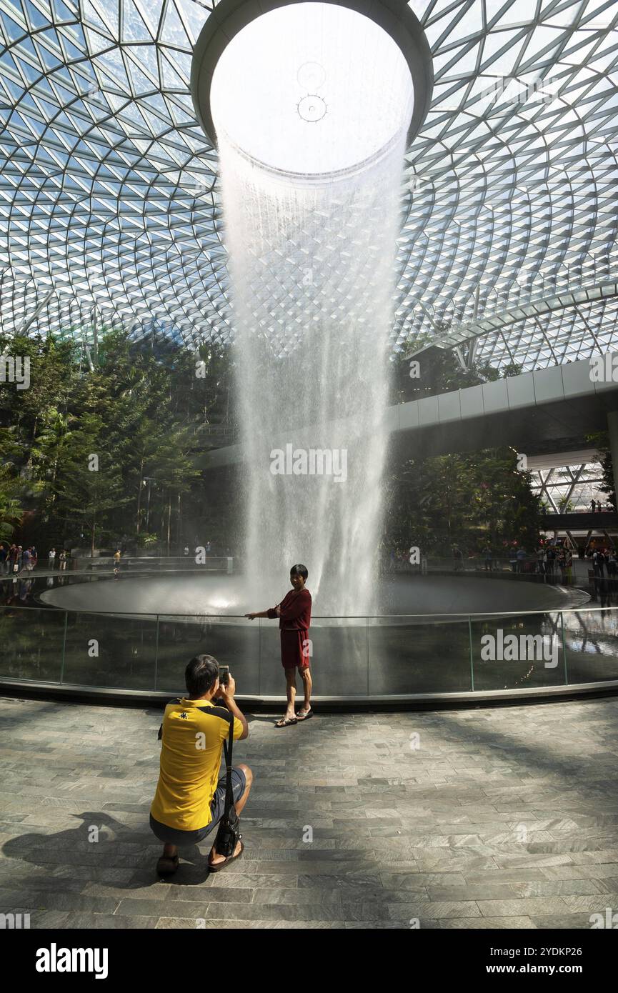 18.04.2019, Singapore, Repubblica di Singapore, Asia, Un uomo scatta una foto della sua donna di fronte alla cascata nel nuovo Jewel Terminal di Changi Int Foto Stock