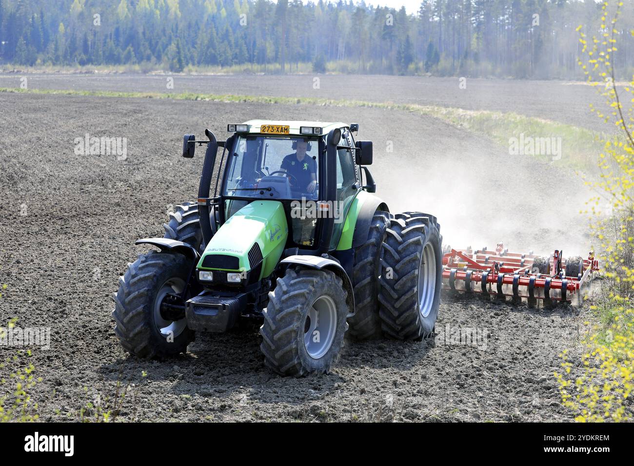 Campo coltivatore con trattore verde Deutz-Fahr Agrotron 135 e erstad NZ con erpice a denti aggressivo in primavera. Salo, Finlandia. 13 maggio 2021 Foto Stock