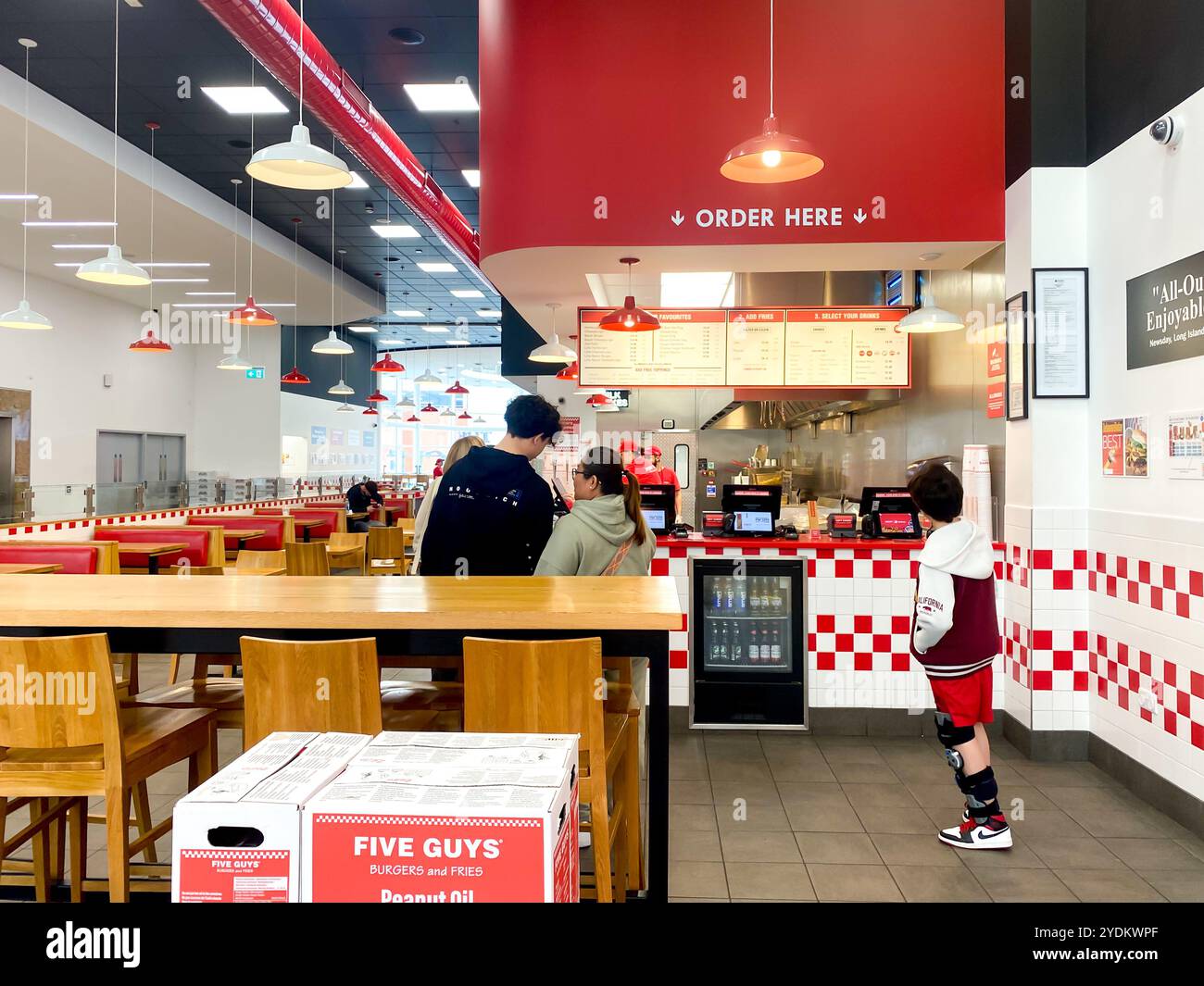 Una famiglia pronta a ordinare cibo in un ristorante Five Guys decorato con i suoi colori rosso e bianco Foto Stock