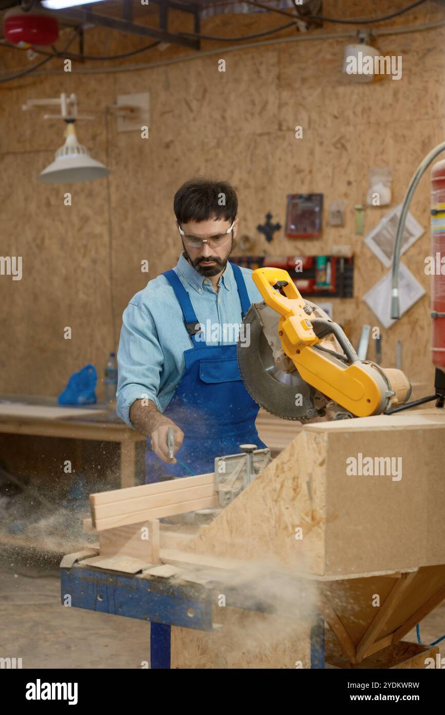 Carpentiere esperto che sega tavole di legno utilizzando una sega circolare rotonda sul banco di lavoro Foto Stock