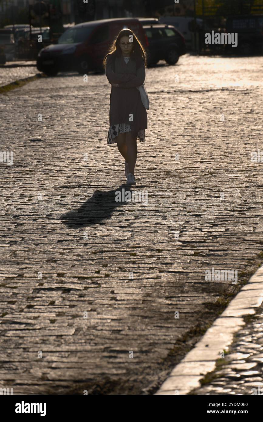La giovane donna triste cammina abbracciandosi sulla strada lastricata del Tesnjar Bazaar nella città di Valjevo, in Serbia Foto Stock