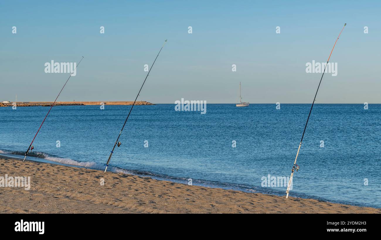 Vista panoramica di tre canne da pesca situate sulla spiaggia di Porto Corallo, Sardegna, Italia, alla luce del tramonto Foto Stock