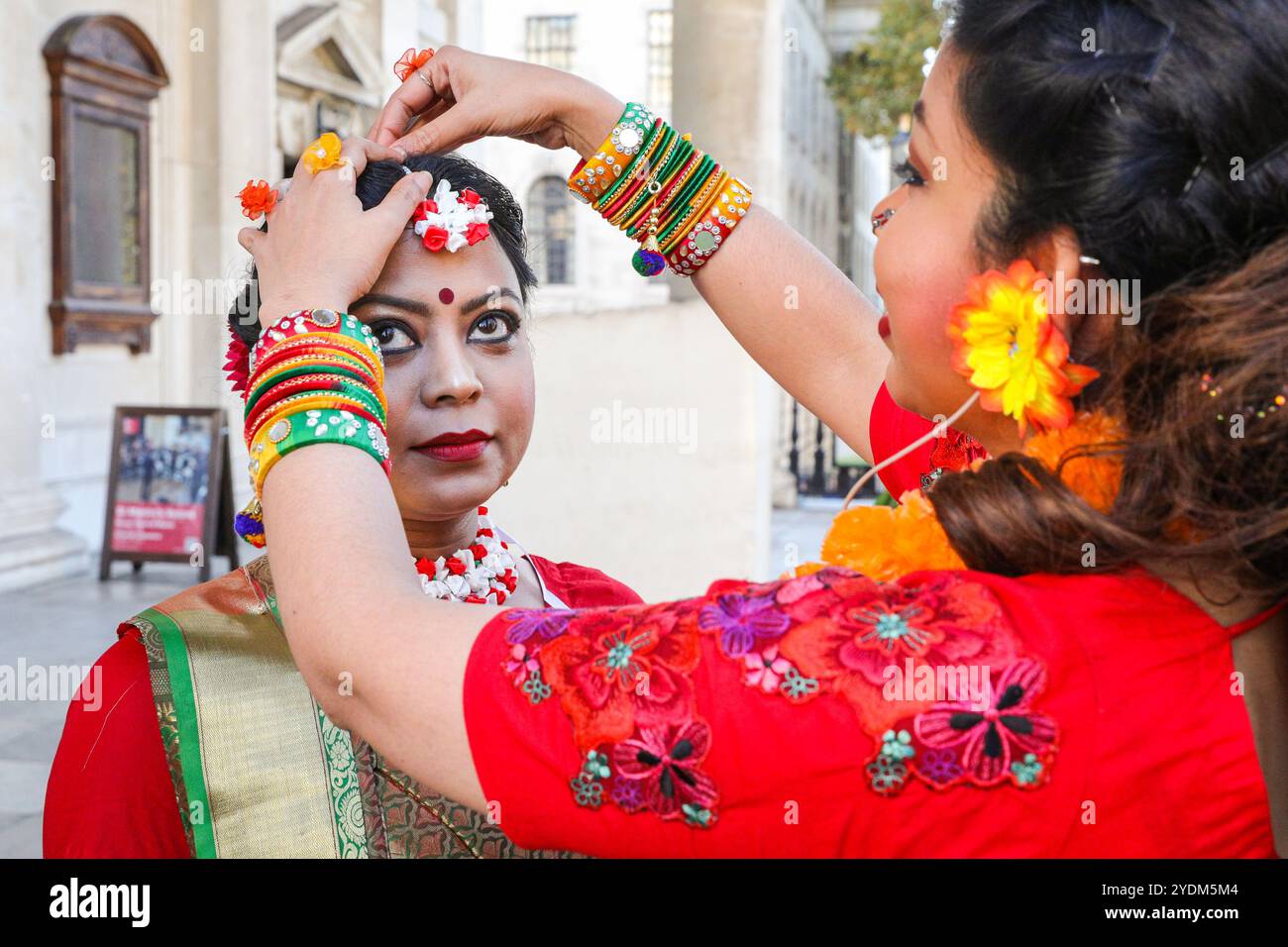 Londra, Regno Unito. 27 ottobre 2024. Vengono applicati fiori intricati. Un gruppo di danza si prepara per la grande sequenza di apertura in seguito, con le modifiche finali a costumi, trucco e decorazioni in corso. La celebrazione della capitale di Diwali, il Festival delle luci, su Trafalgar Square mette in mostra elementi della cultura delle comunità indù, sikh e giainiste di Londra con vivaci danze, musica, attività, bancarelle del mercato e cibo. Crediti: Imageplotter/Alamy Live News Foto Stock