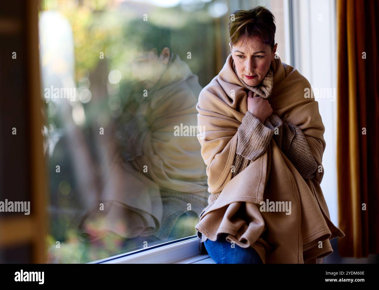 Donna avvolta in coperta che mantiene caldo Foto Stock