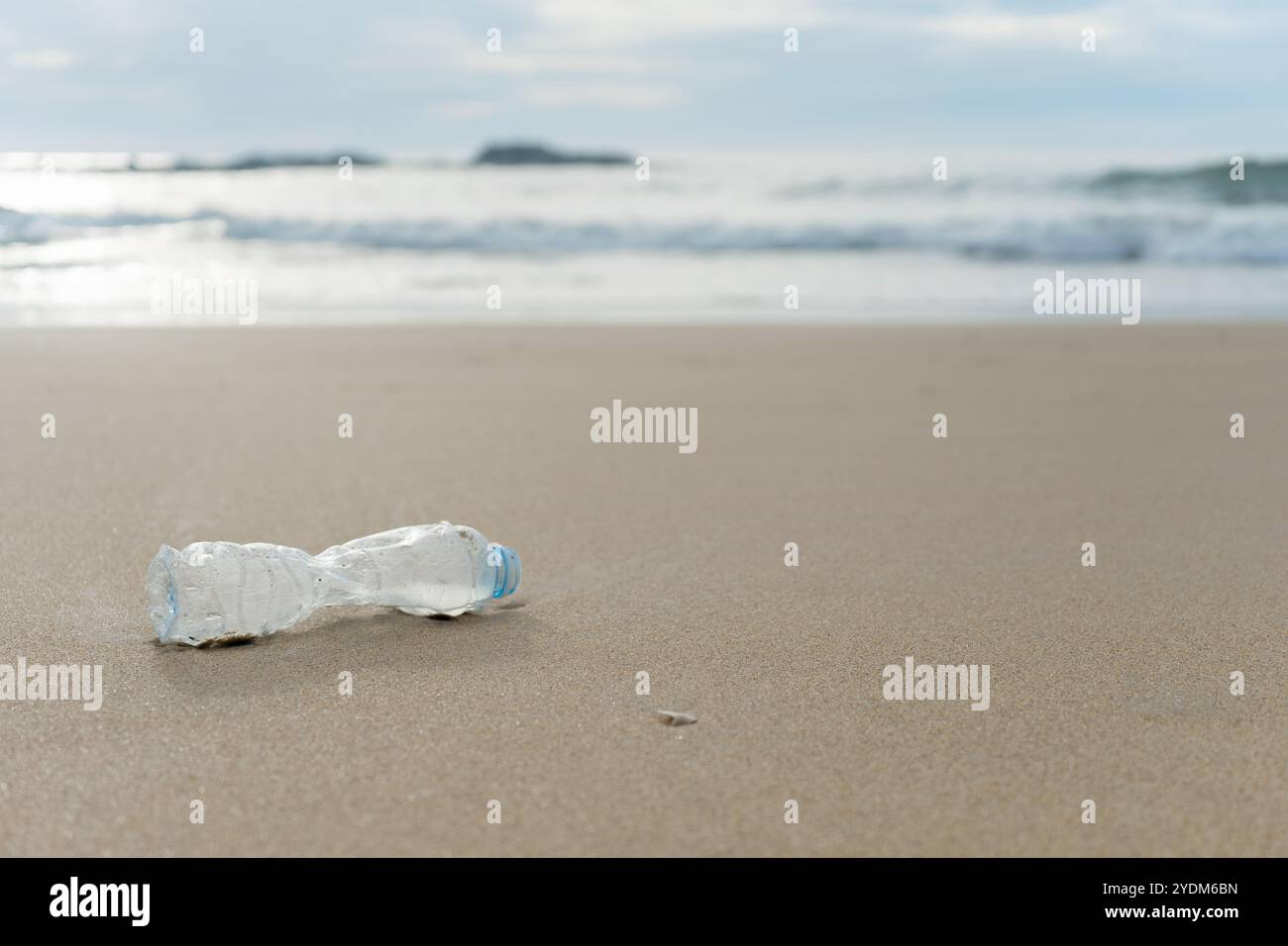 Una bottiglia di plastica vuota giace sulla spiaggia deserta di sabbia Foto Stock