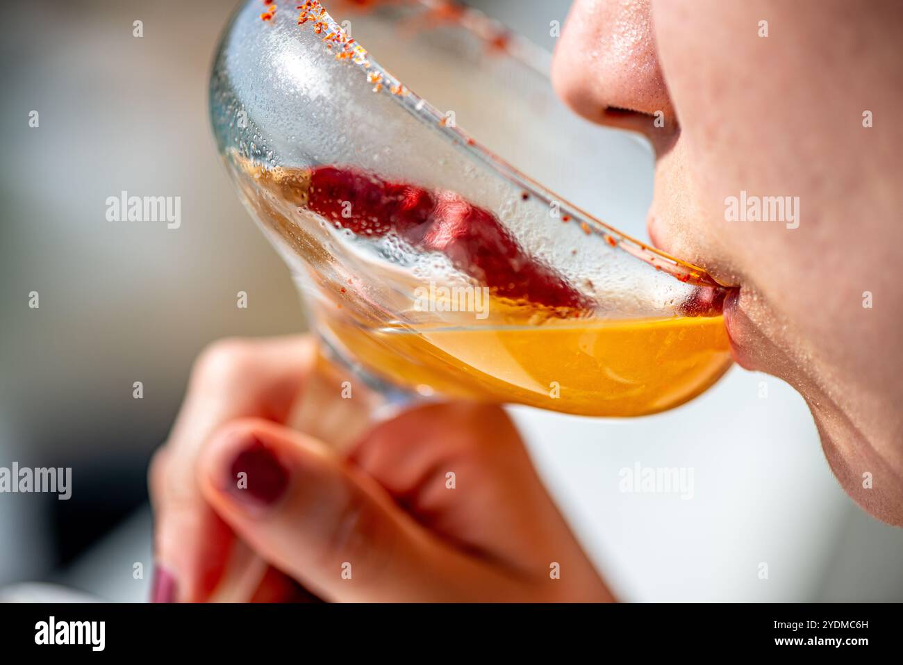 Donna elegante che sorseggia un cocktail di margarita al chili in un ambiente vivace, catturando l'essenza delle spezie e del rinfresco in questo momento di drink unico. Foto Stock