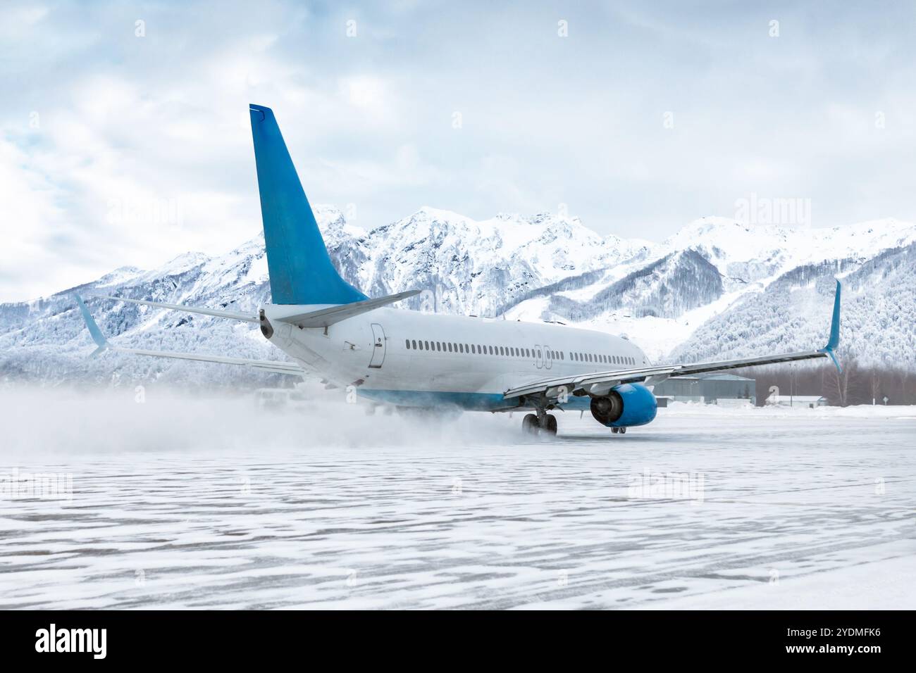 Passeggeri in volo all'aeroporto in una forte tempesta di neve sullo sfondo di alte montagne innevate Foto Stock