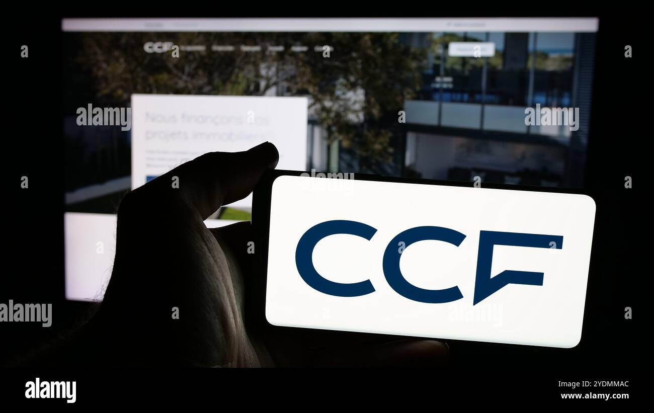 Persona che detiene lo smartphone con il logo dell'azienda Credit Commercial de France (CCF) sullo schermo davanti al sito Web. Mettere a fuoco il display del telefono. Foto Stock