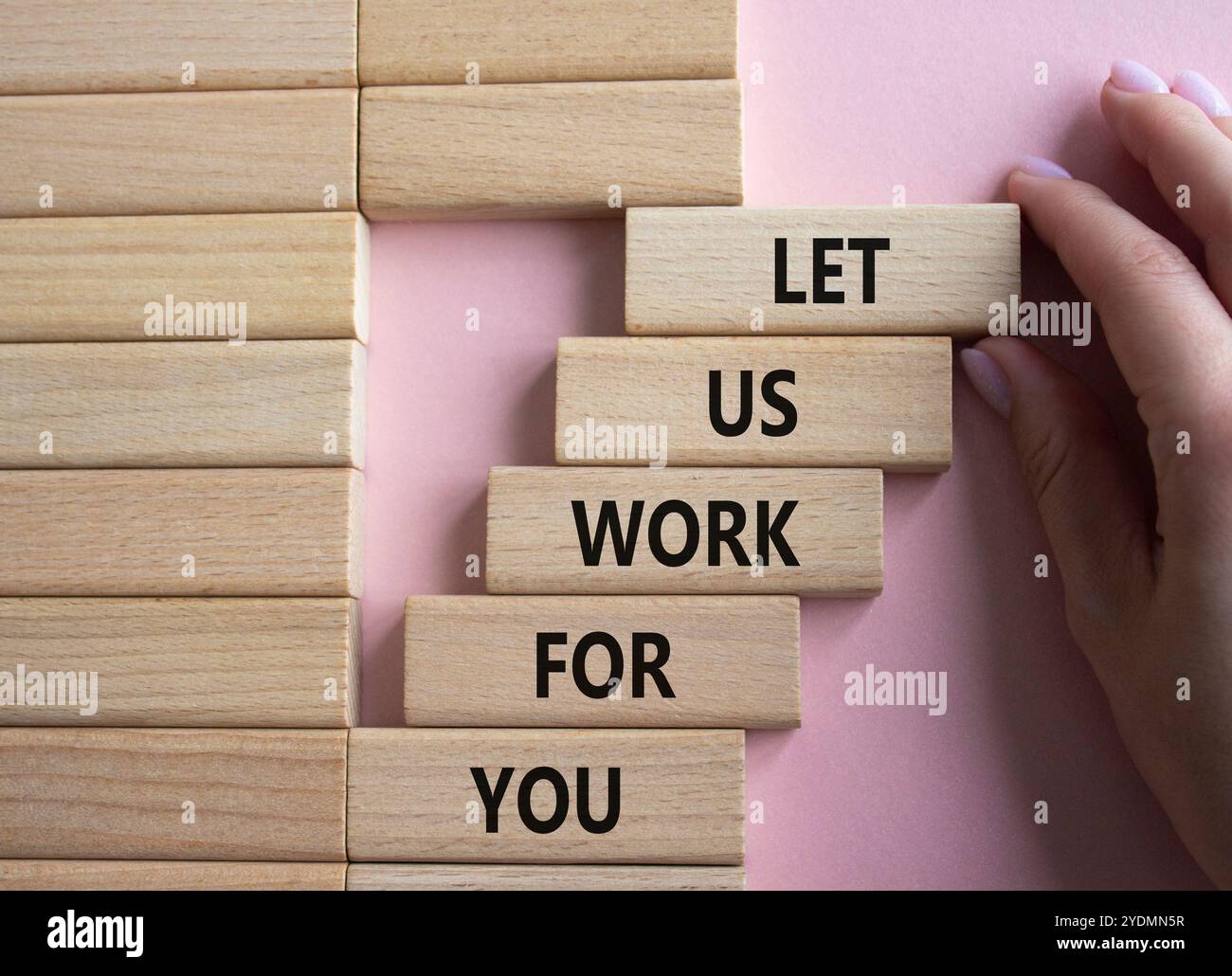 Fateci lavorare per voi, simbolo. Blocchi di legno con le parole lasciaci lavorare per te. Bellissimo sfondo rosa. Mano d'affari. Affari e lasciaci lavorare per yo Foto Stock