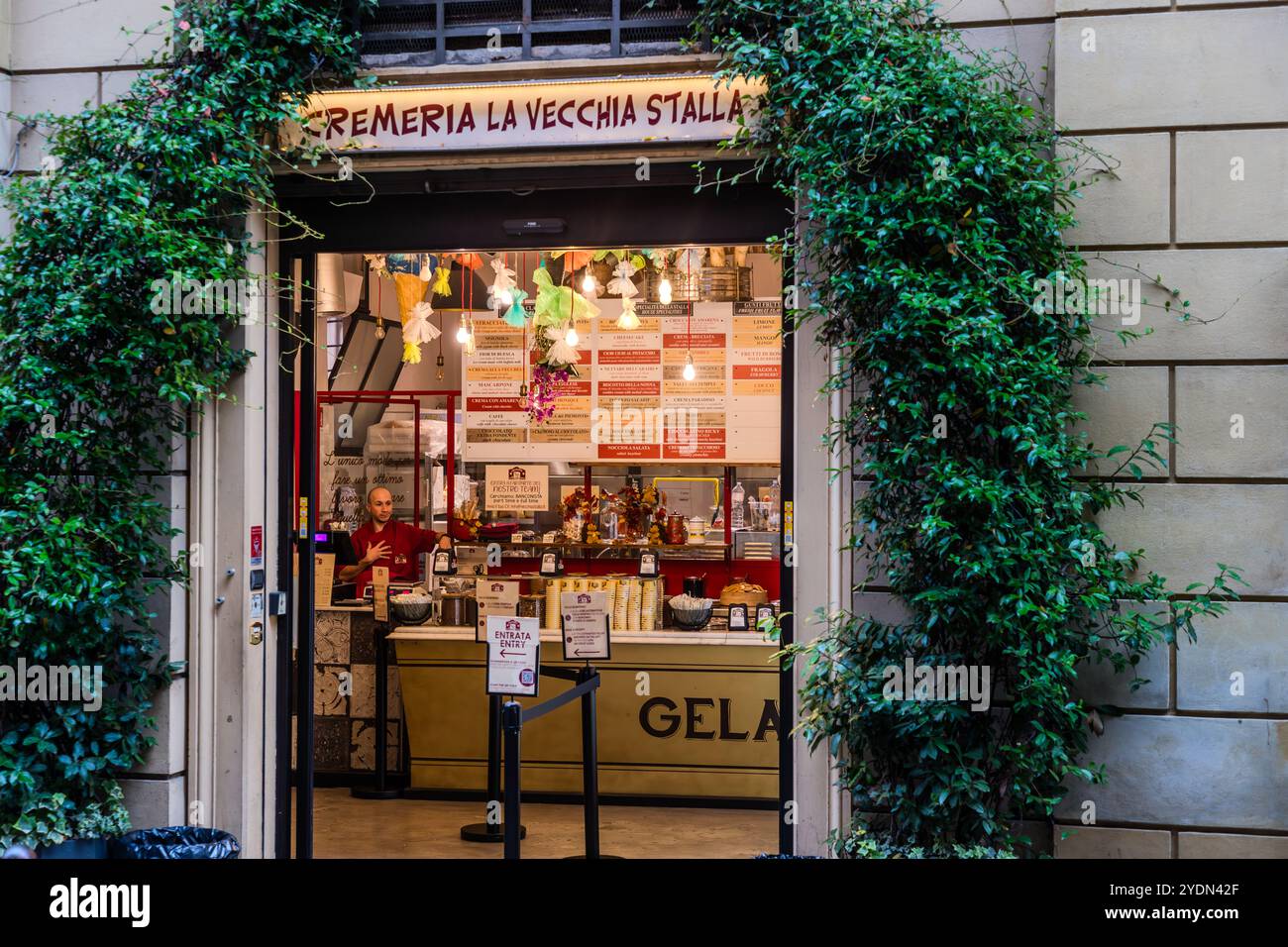 La gelateria Cremeria La Vecchia Stalla attira i visitatori con piante rampicanti in fiore che incorniciano il suo ingresso in Via Guglielmo Oberdan. Via Guglielmo Oberdan, Bologna, Emilia-Romagna, Italia. Foto Stock