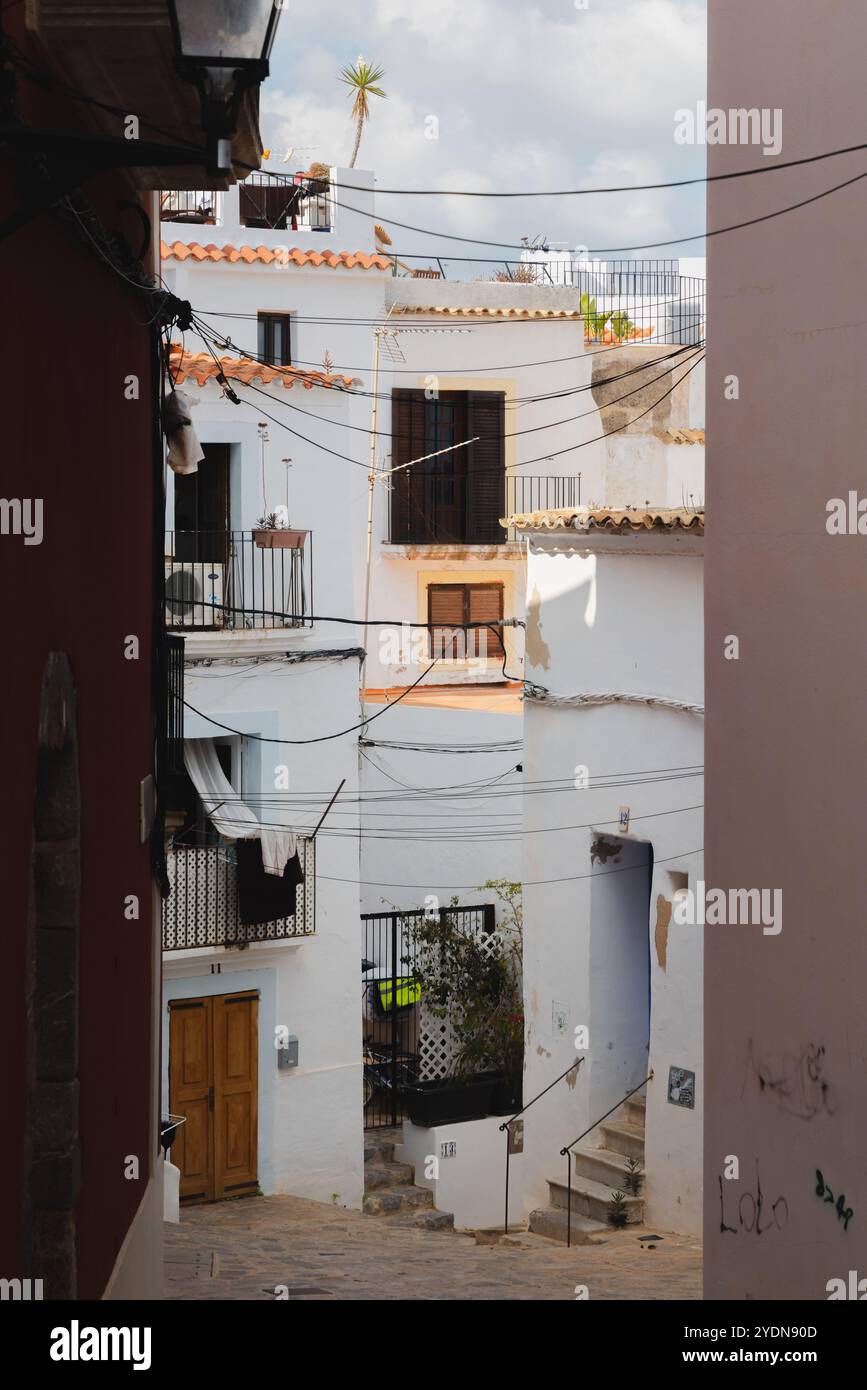 Tranquilla strada stretta nella città vecchia di Ibiza, con affascinanti edifici bianchi con balconi tradizionali e una rustica atmosfera mediterranea Foto Stock