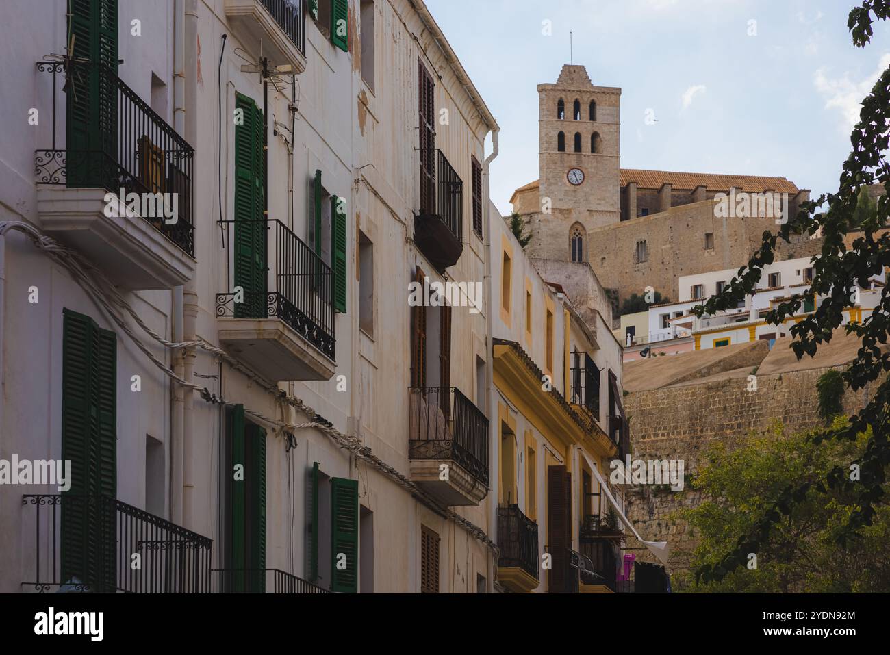 Incantevole vista della città vecchia di Ibiza con i suoi balconi tradizionali, le persiane verdi e l'iconica torre del castello, che mostra la bellezza senza tempo di questo me Foto Stock